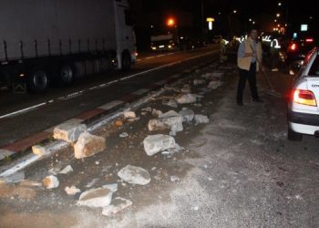 Un camión volquete desparrama su carga de piedra por la N-550 en Arcade