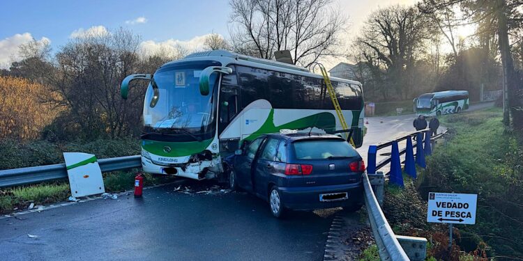Los bomberos sacan por el techo a tres pasajeros de un bus escolar que chocó con un turismo